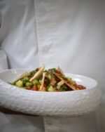 Professional chef instructor guiding student in global cuisine class